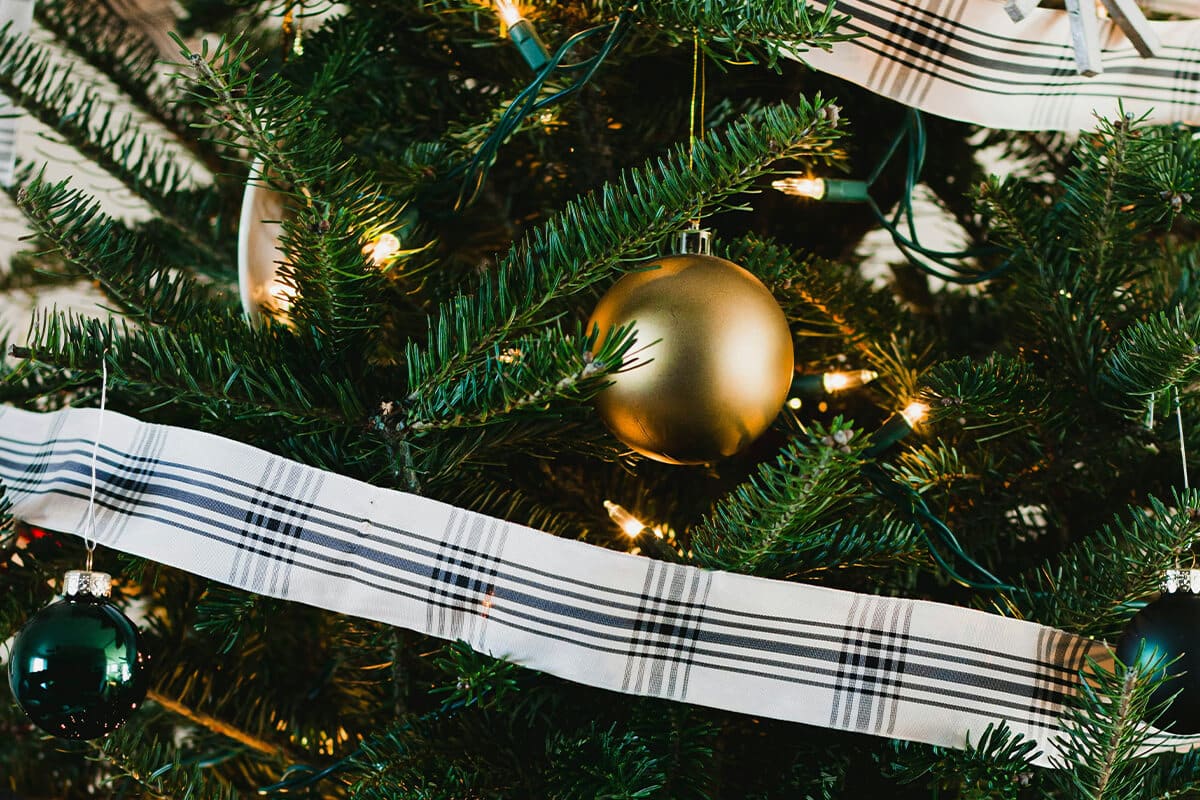 Weihnachtsbaum mit goldenen Weihnachtskugeln und weiß-karrierter Banderole